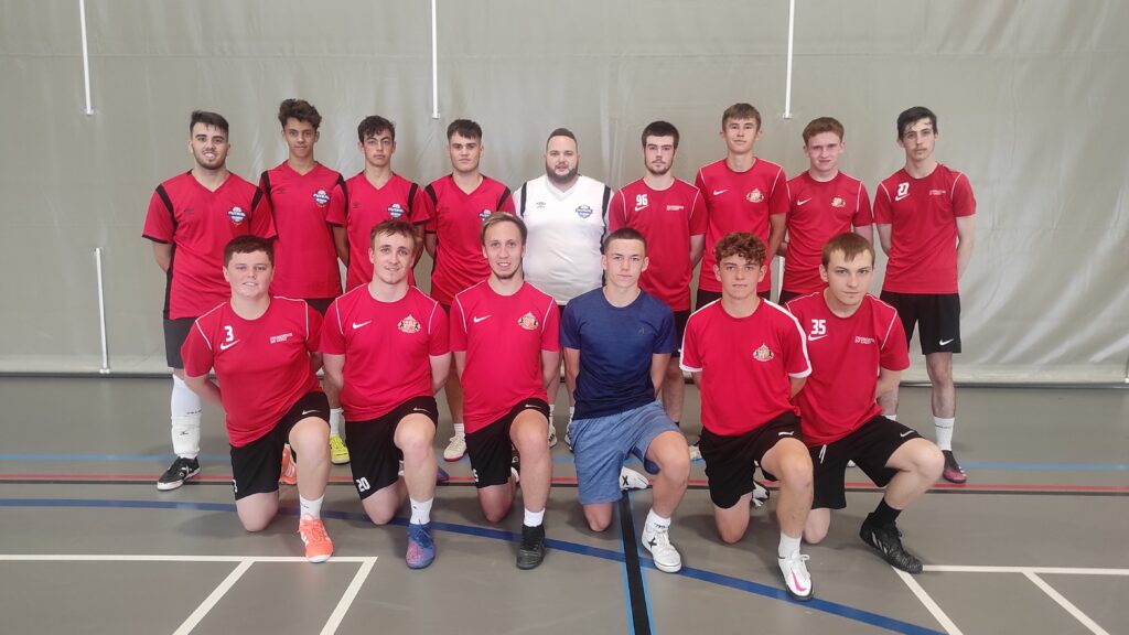 Un grupo de adolescentes sonríe mientras juega futsal en el Campamento de Verano en Sunderland - Julio 2024.